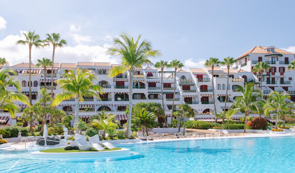 Hotelgebäude mit Palmen und Swimmingpool in Teneriffa.