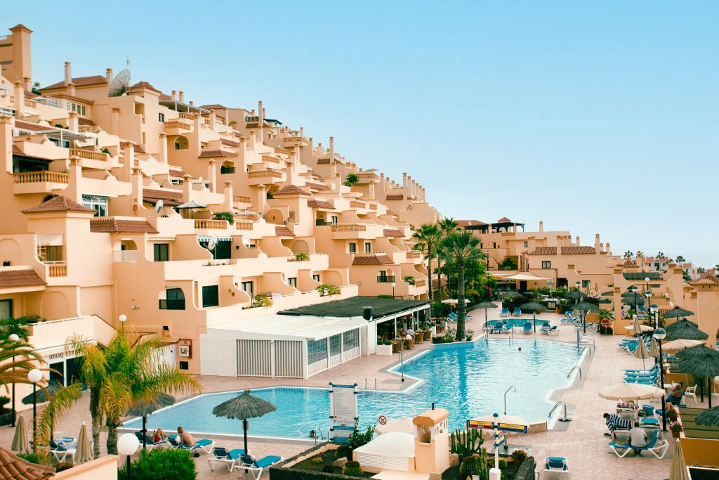 Wohnkomplex mit Pool in Costa Adeje, Teneriffa, umgeben von Sonnenschirmen und Liegestühlen.