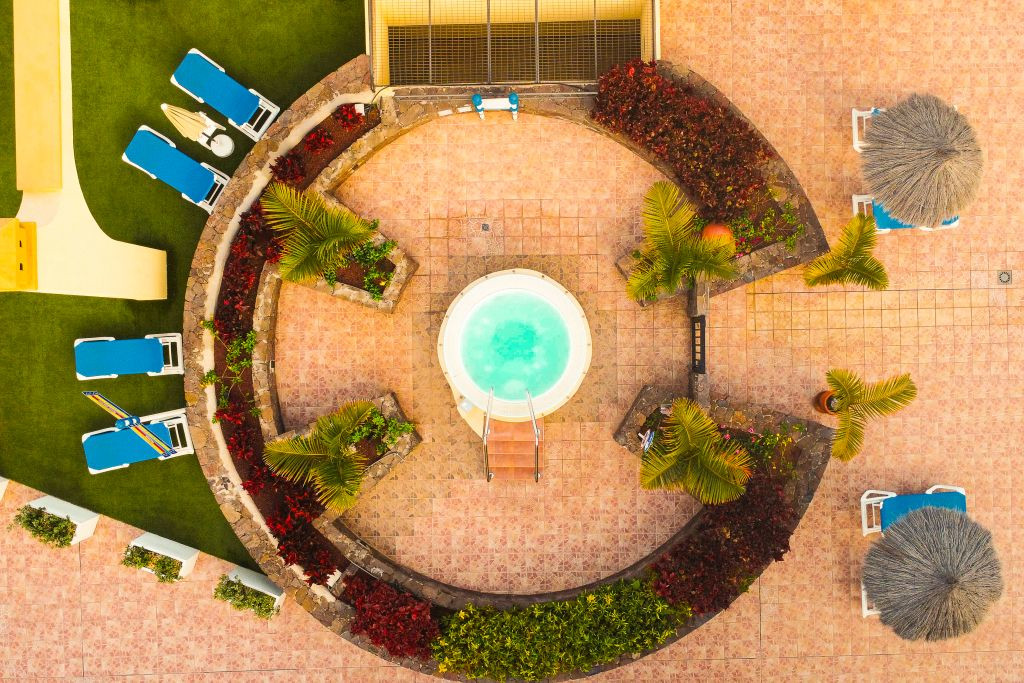 Ansicht eines kreisförmigen Pools mit Liegestühlen und Palmen in einem Hotel in Tenerife.