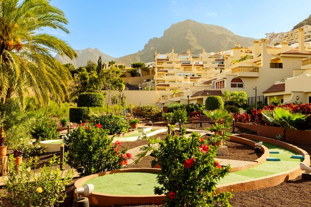 Minigolfplatz mit Pflanzen vor beige Wohnungen in Costa Adeje, Teneriffa.