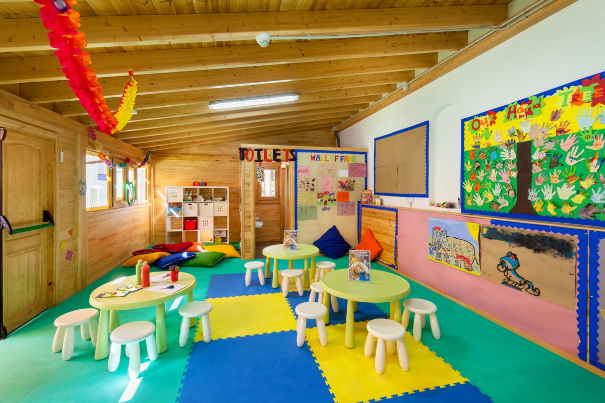 Klassenzimmer in Teneriffa mit bunten Tischen, Stühlen und Kinderzeichnungen an der Wand.