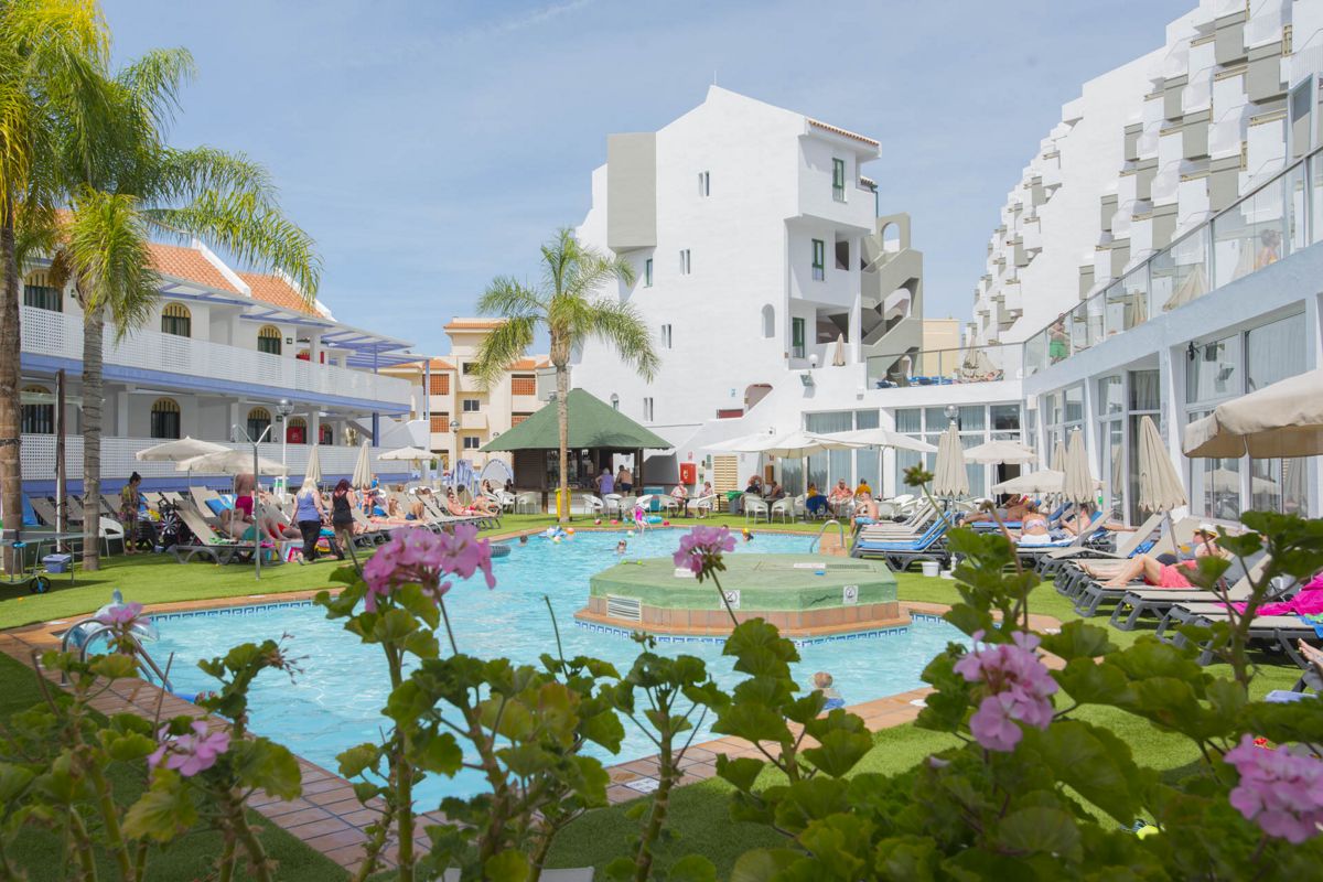Außenpoolbereich in einem Hotel in Teneriffa mit Gästen beim Sonnenbaden.