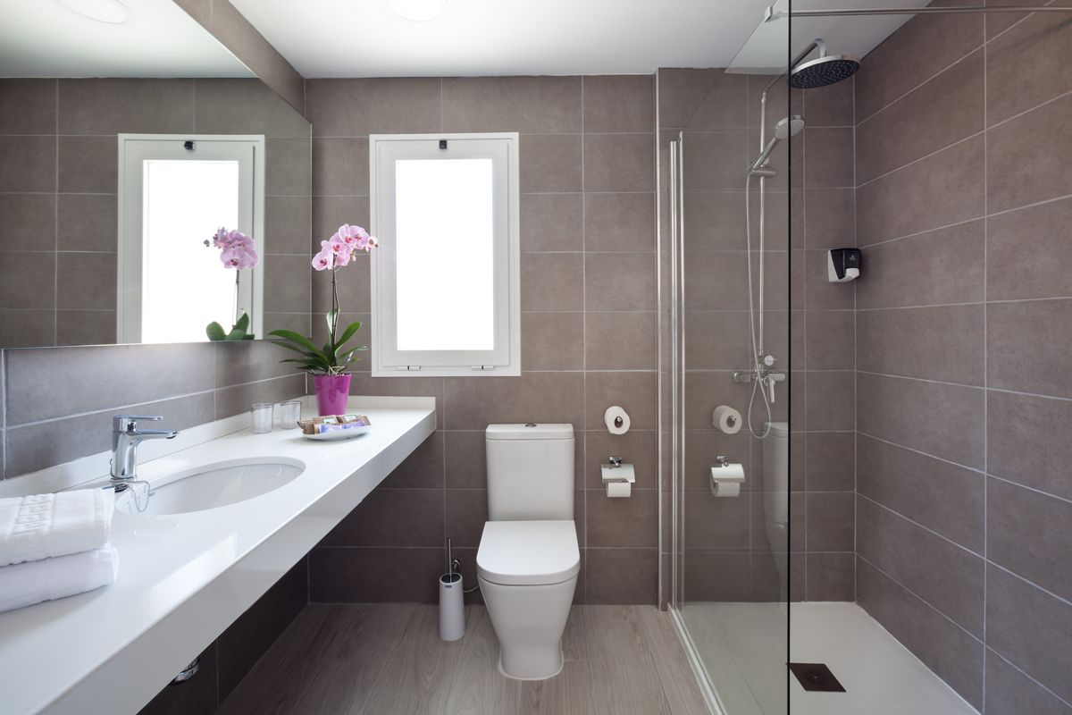 Modernes Badezimmer in Puerto de la Cruz mit Dusche, Waschbecken, Toilette und Orchidee.