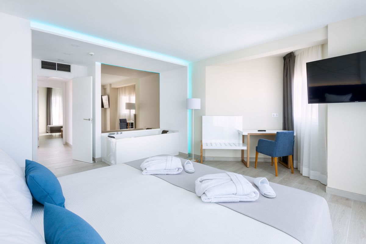 Moderne Hotelzimmeransicht in Teneriffa mit Doppelbett, Sessel und Fernseher.