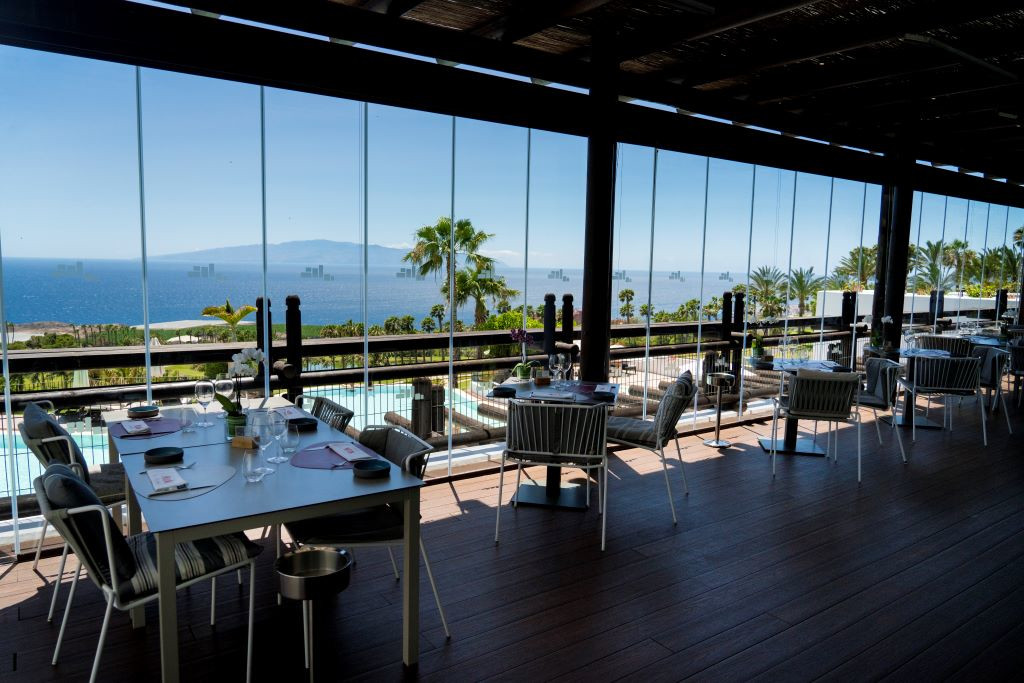 Restaurant mit Meerblick in Adeje, Teneriffa, mit gedeckten Tischen und Panorama-Aussicht.