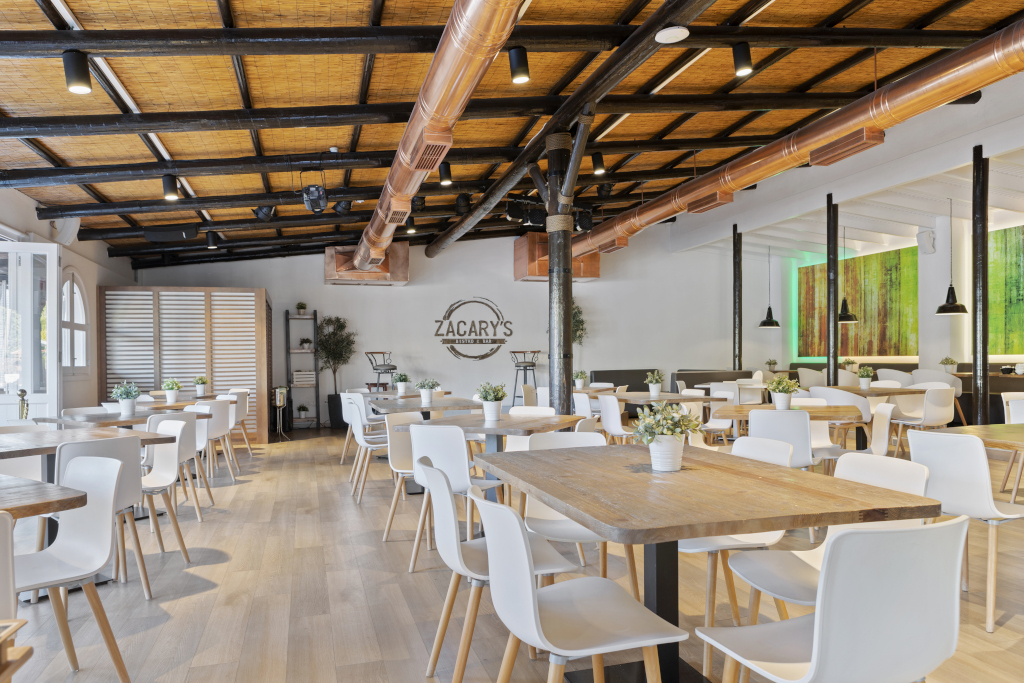 Moderne Innenansicht des Zacary's Restaurants in Santa Cruz de Tenerife mit Tischen und Stühlen.
