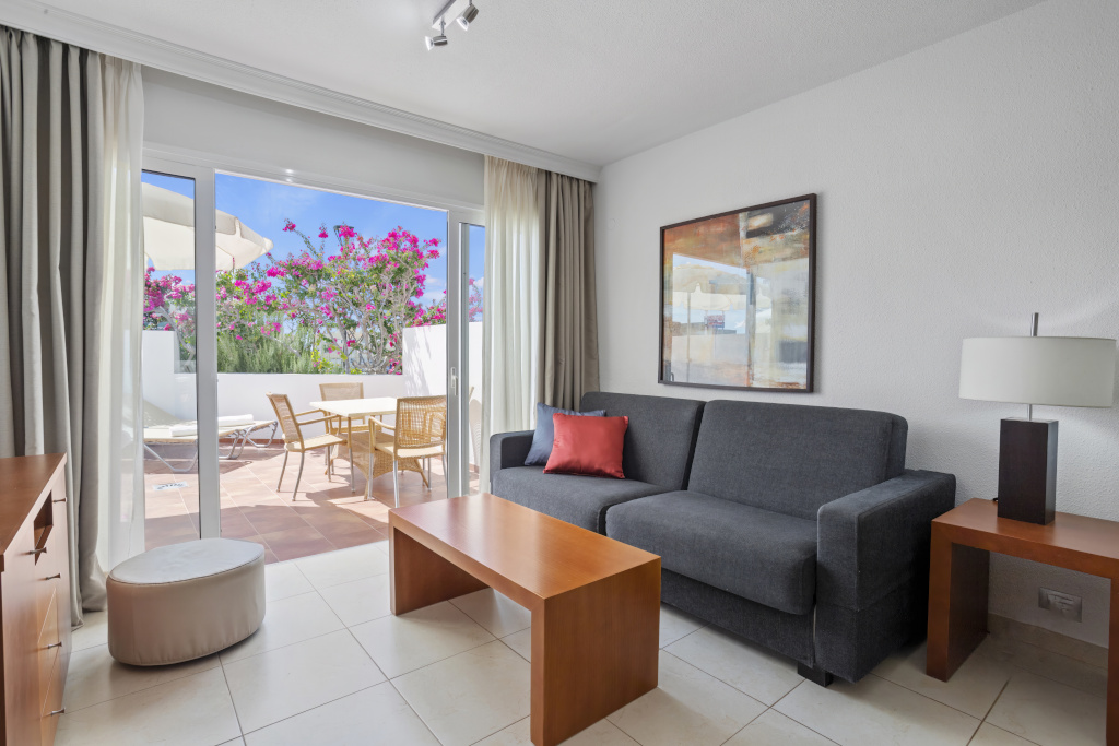 Wohnzimmer in Teneriffa mit Sofagarnitur und Zugang zur Terrasse mit Pflanzen.