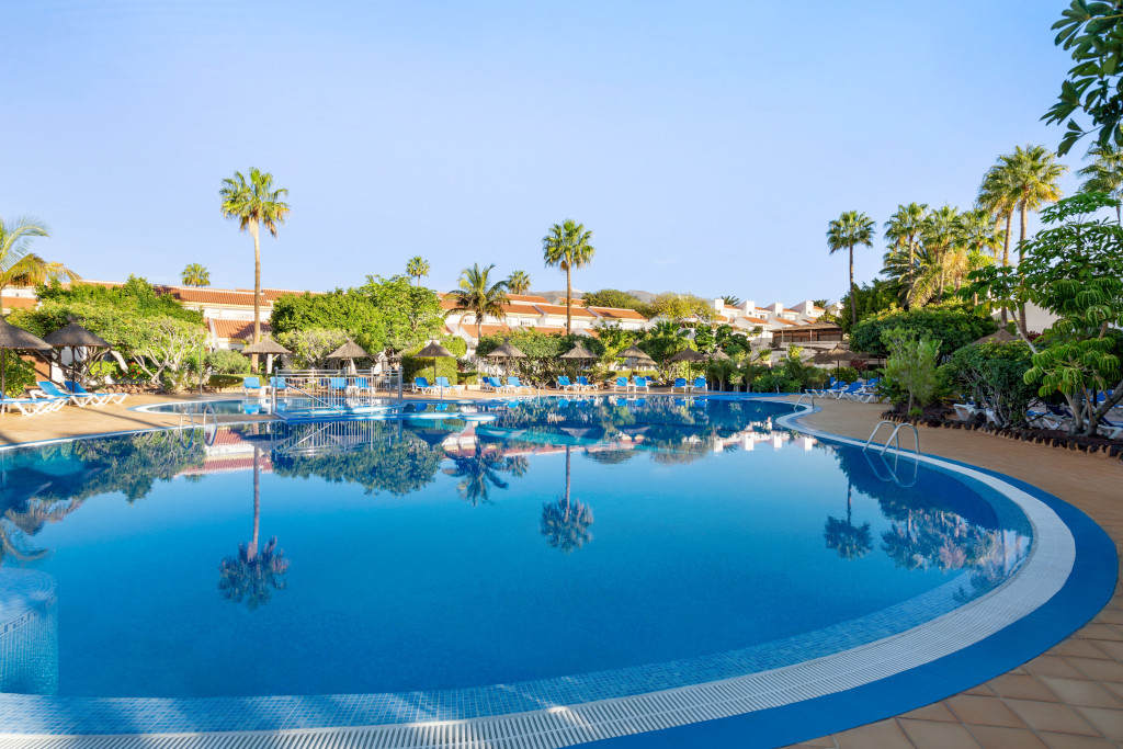 Poollandschaft mit Palmen und Liegen in einem Resort auf Teneriffa.
