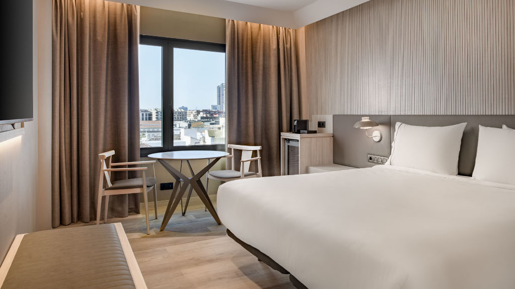 Modernes Hotelzimmer mit Doppelbett, Tisch und Stühlen, Ausblick auf Adeje.