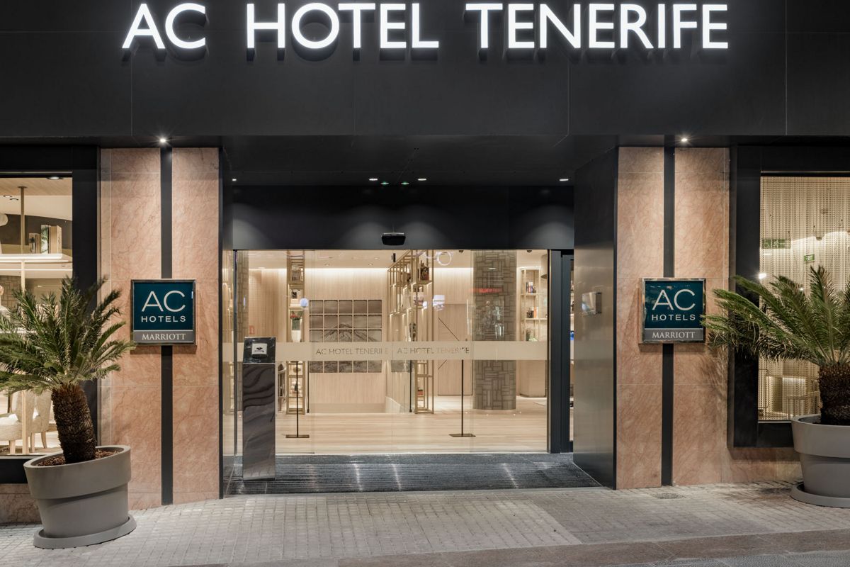 AC Hotel Eingang bei Nacht in Tenerife mit beleuchtetem Schild und Pflanzen.