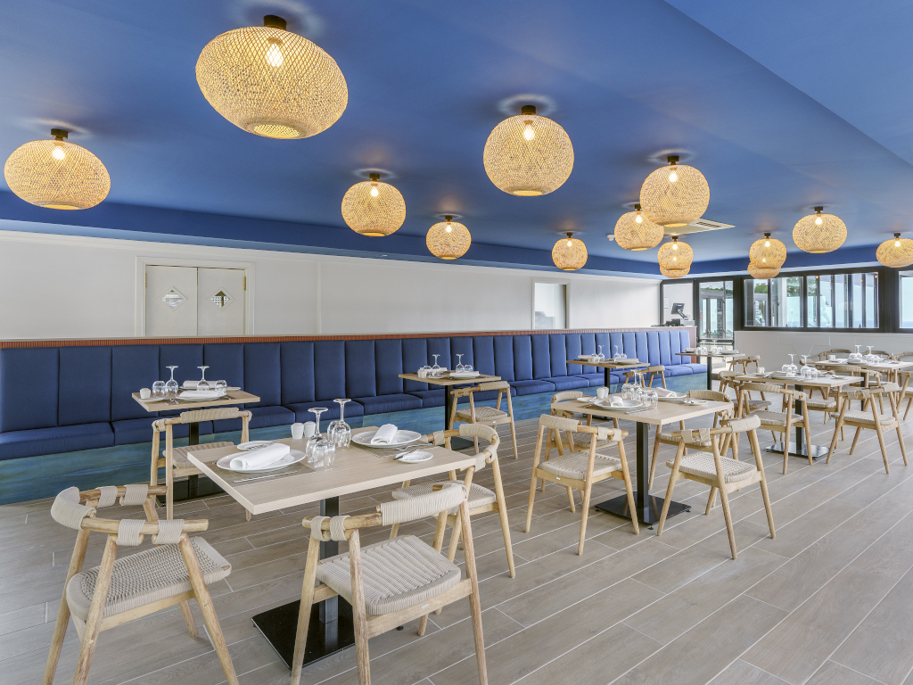 Moderne Restaurant-Innenraum mit blauer Decke und hölzernen Tischen in Puerto de la Cruz, Teneriffa.