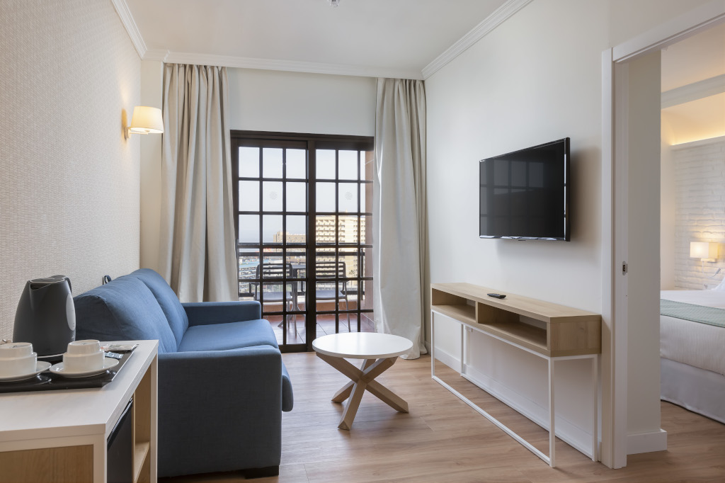 Wohnzimmer mit Sofa, Tisch, Fernseher und Balkonblick in einem Hotel in Tenerife.