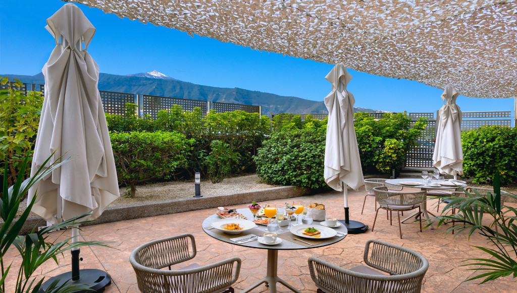 Außenterrasse mit Frühstückstischen, Sonnenschirmen und Blick auf den Teide in La Orotava.