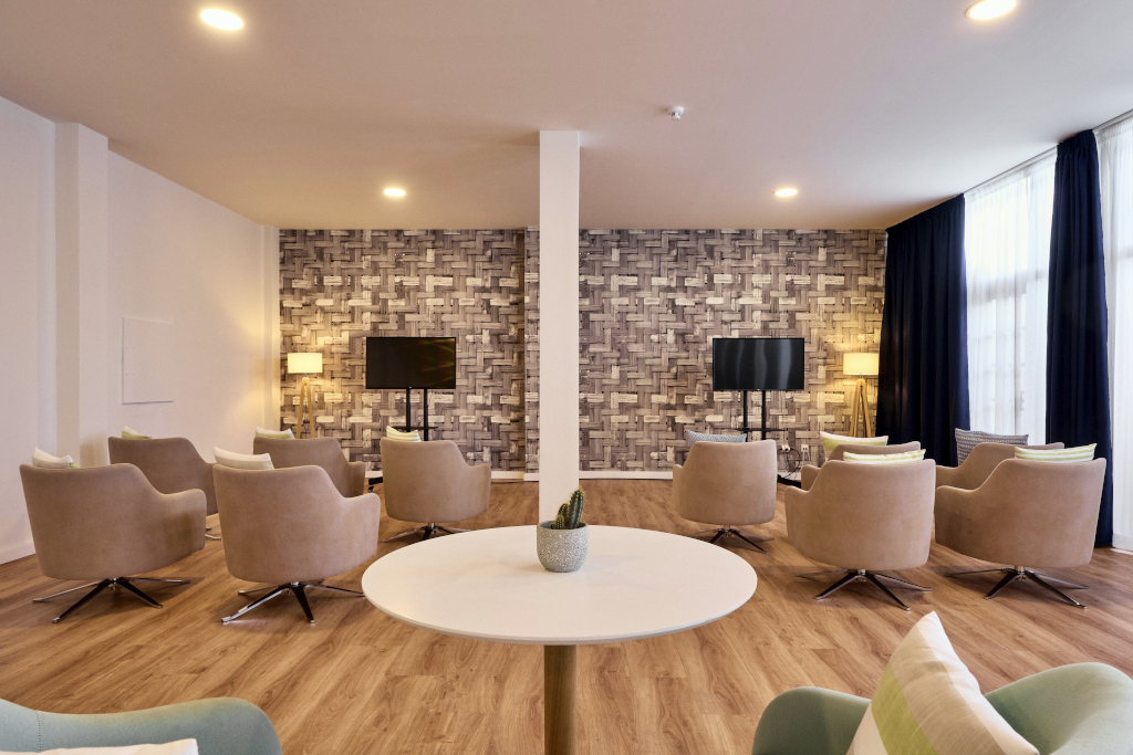 Moderner Loungebereich mit Sesseln und TVs, geeignet für Meetings in Tenerife.