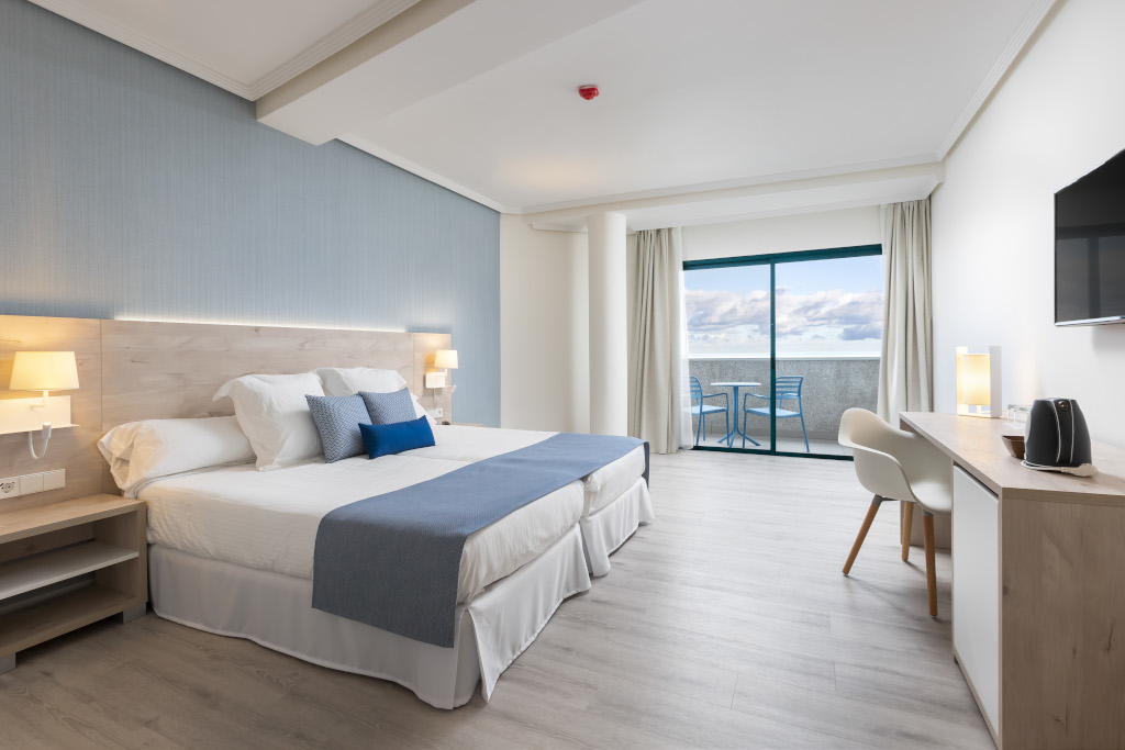 Hotelzimmer in Tenerife mit Doppelbett und Balkon mit Meerblick.