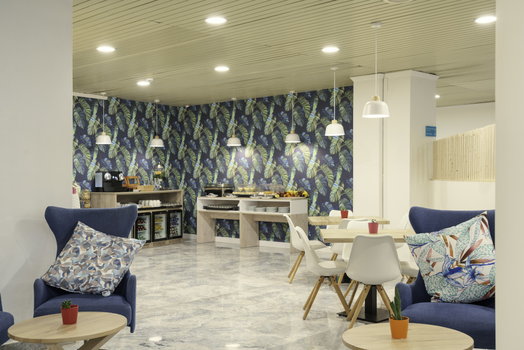 Moderner Cafeteria-Bereich mit Pflanzenmusterwand und Sitzmöbeln in Puerto de la Cruz, Teneriffa.