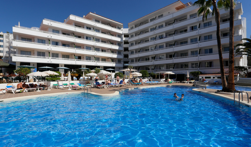 Hotel mit Pool im Freien, Palmen und Sesseln in Puerto de la Cruz, Teneriffa.