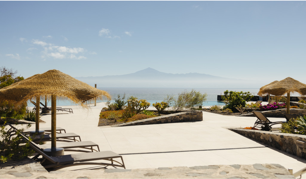 Sonnenliegen und Strohdächer mit Blick auf Teide in Teneriffa.