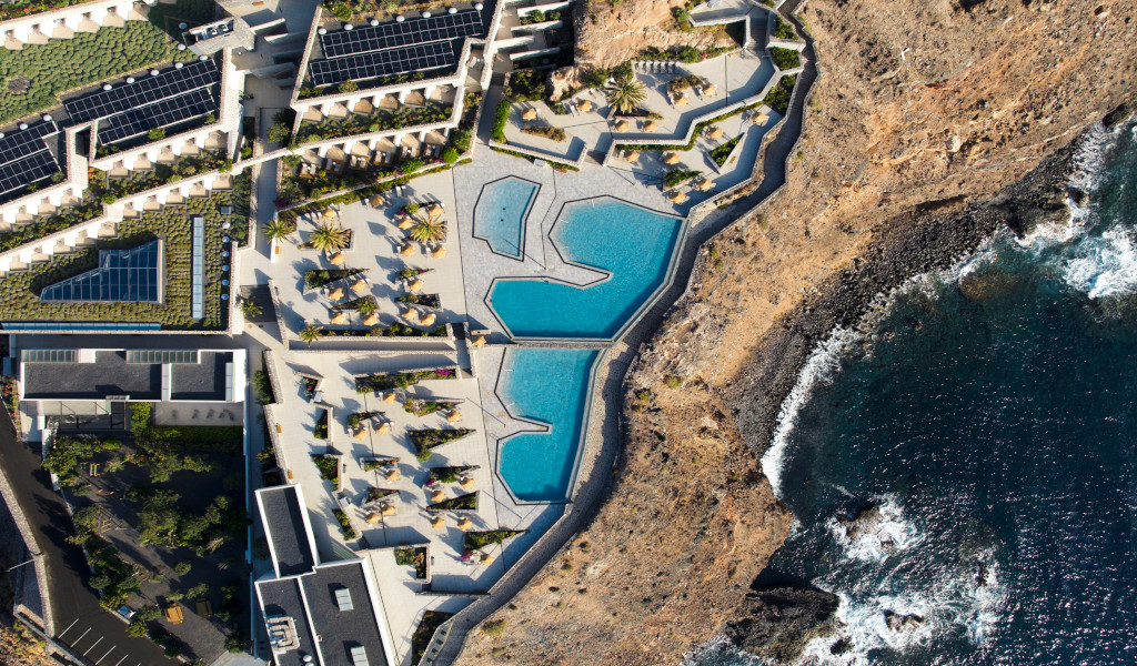 Luftaufnahme eines Küstenhotels mit Solarpanelen und Pools in Tenerife.