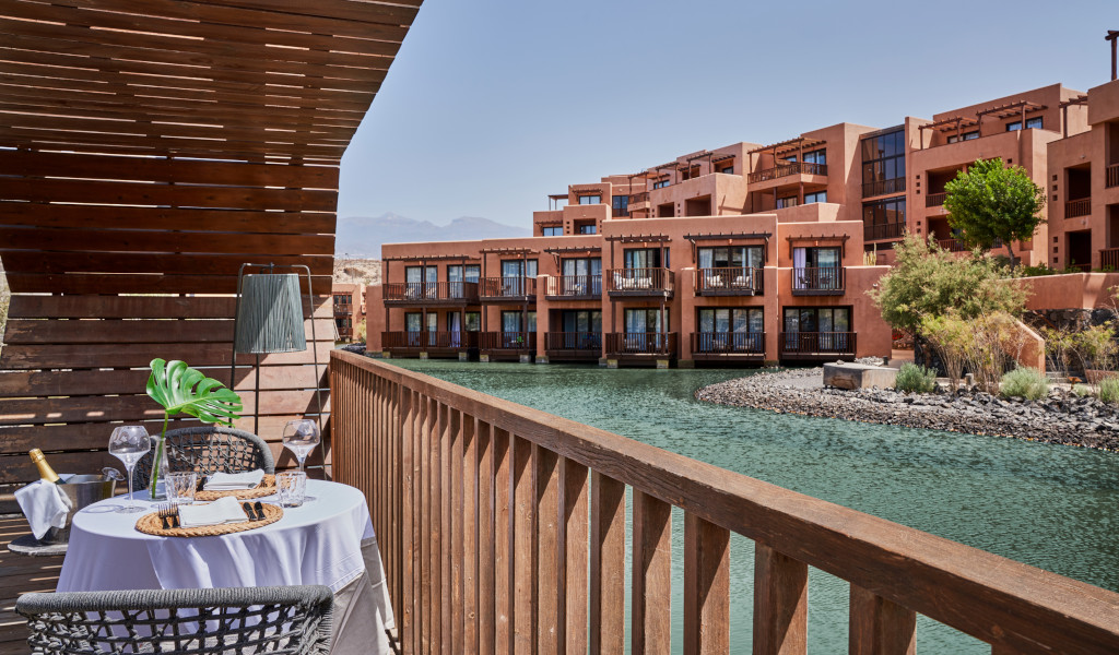 Terrasse mit Tisch und Stühlen neben einem Wasserkanal in einem Touristenkomplex auf Teneriffa.