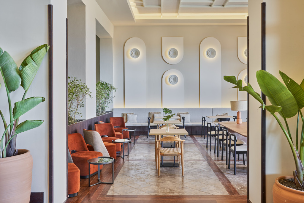 Zimmer mit Sesseln und Tischen in einem Hotel auf Teneriffa, dekoriert mit Pflanzen und Wandpaneelen.