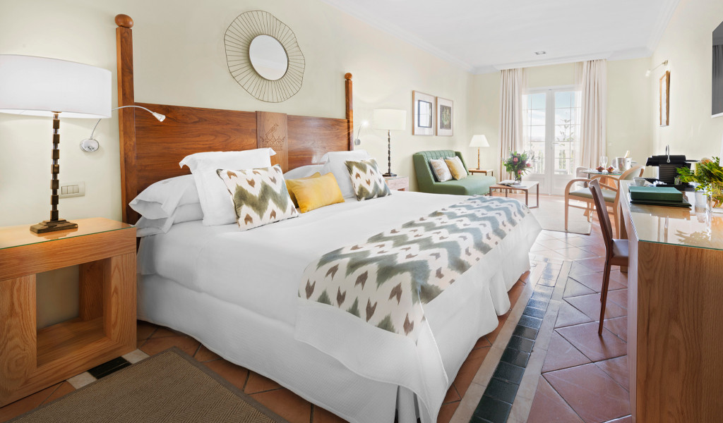 Hotelzimmer mit großem Bett, Holzmöbeln und Balkonblick in Tenerife.