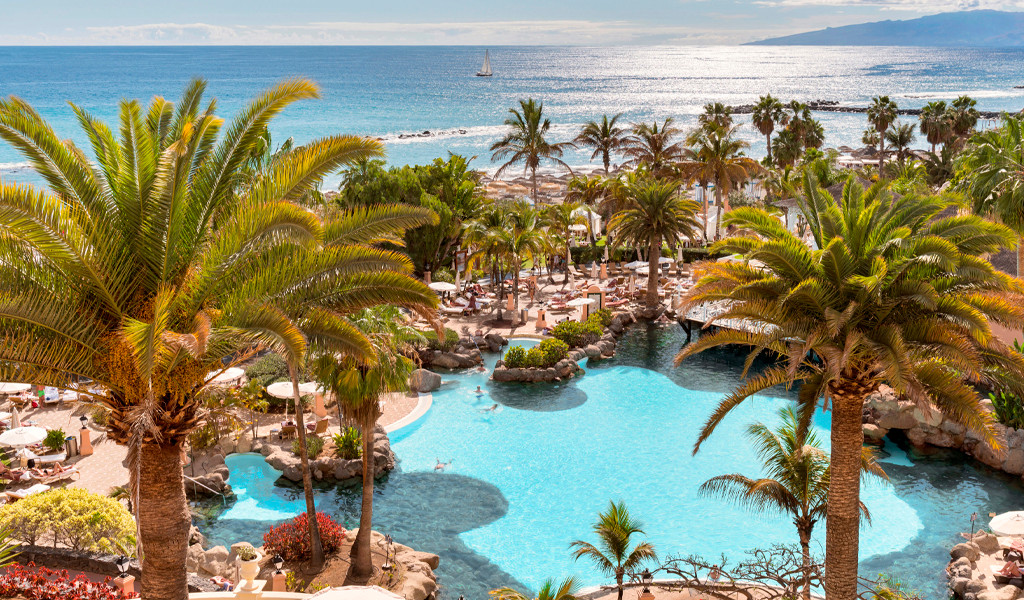 Poollandschaft mit Palmen und Meerblick in Costa Adeje, Teneriffa.