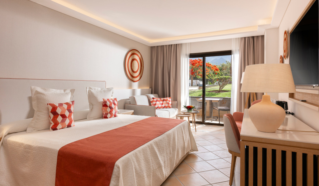 Modernes Hotelzimmer mit Bett, Sofa und Balkonblick in Teneriffa.