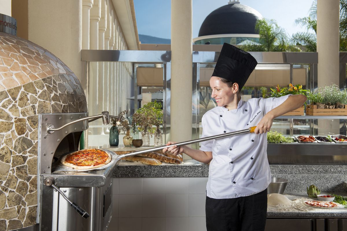 Köchin backt Pizza im Holzofen in einem Restaurant in Teneriffa.