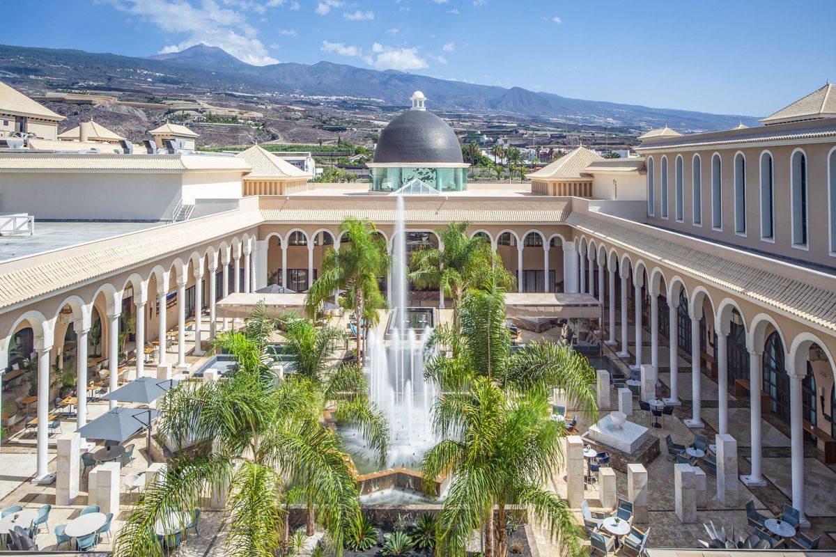 Mittelmeer-Hotel mit zentralem Brunnen und Bergen im Hintergrund in Costa Adeje, Teneriffa.