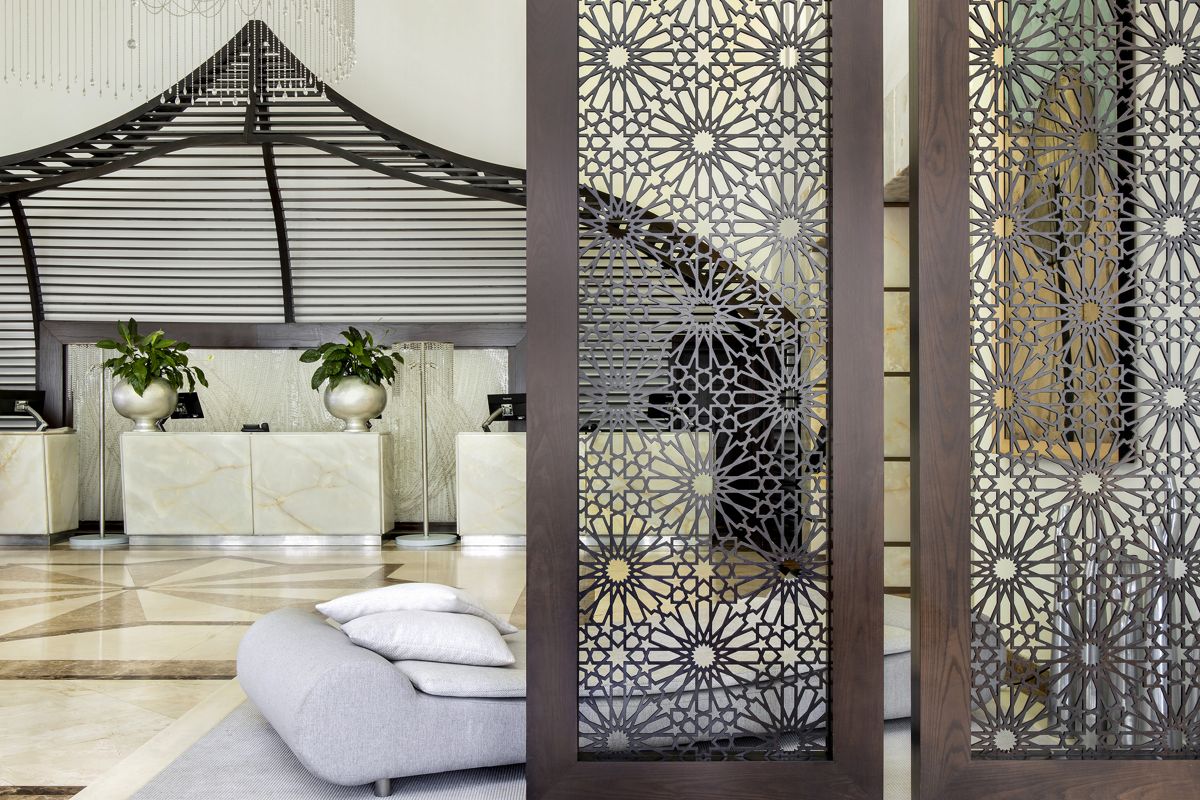 Empfangsbereich eines Hotels in Tenerife mit Pflanzen und kunstvollen Gitterpaneelen.