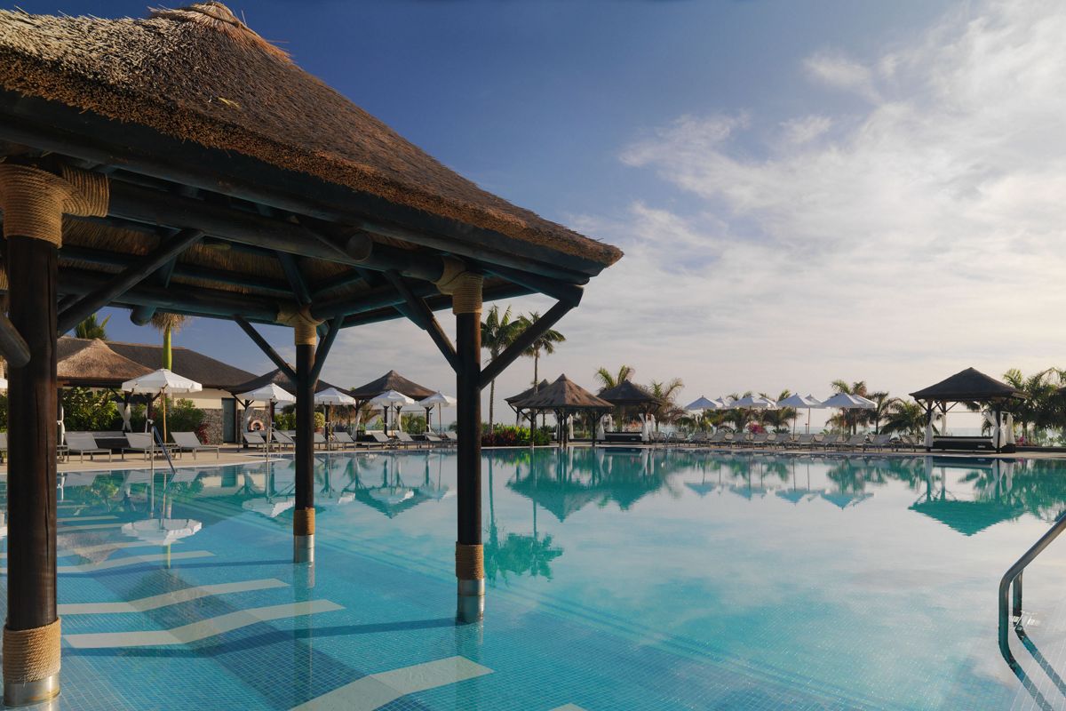 Pool mit Palmen und Sonnenschirmen im Hotel in Tenerife.