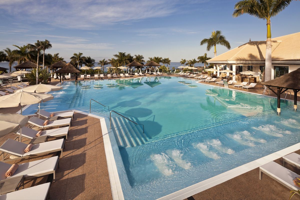 Pool mit Liegestühlen und Palmen in Costa Adeje, Teneriffa.