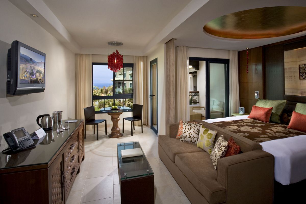 Hotelzimmer mit Sofa, Bett, Tisch und Stühlen, mit Blick auf Costa Adeje in Teneriffa.