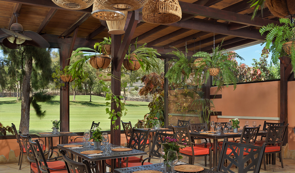Überdachte Terrasse mit Pflanzen und gedeckten Tischen im Restaurant von Tenerife.