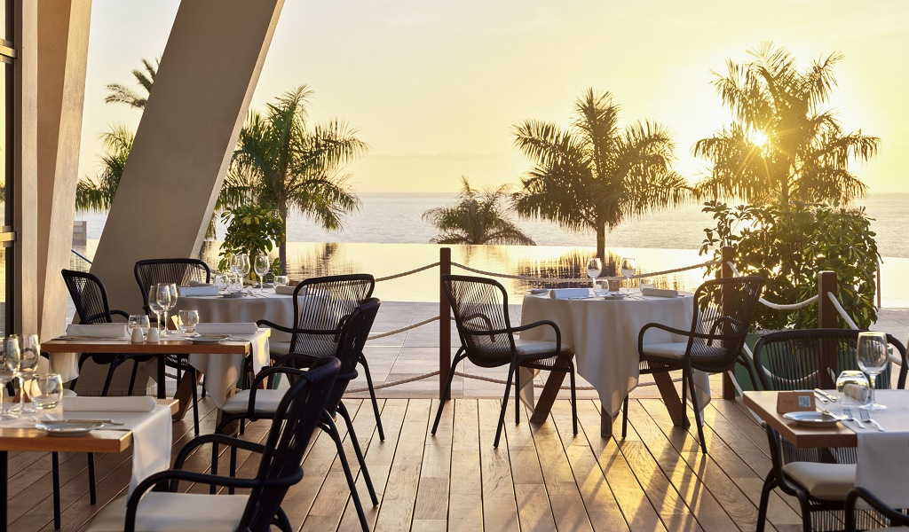 Terrasse eines Restaurants in Teneriffa mit Blick auf den Ozean bei Sonnenuntergang.