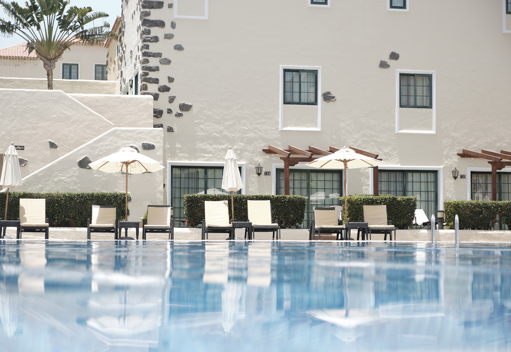 Liegestühle und Sonnenschirme am Pool in einem Hotel in Teneriffa.