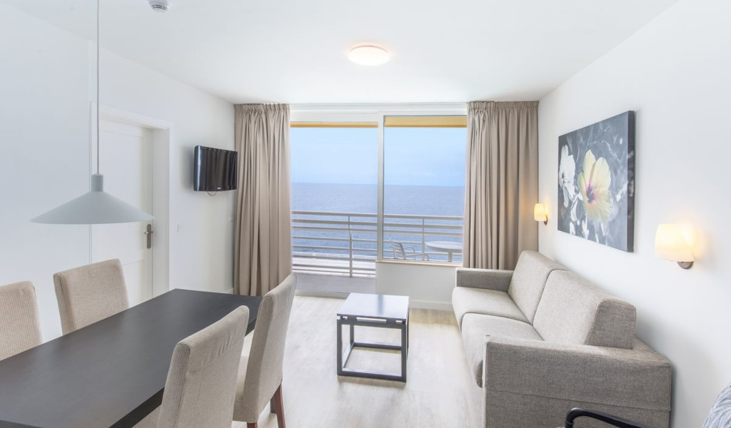 Wohnzimmer mit Essbereich, Sofa, TV und Meerblick in einem Apartment in Teneriffa.