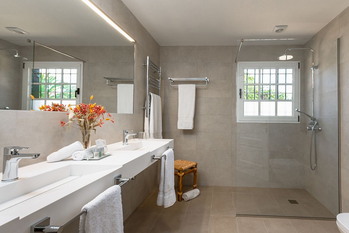 Modernes Badezimmer mit Doppelwaschbecken, Handtüchern und Dusche in Tenerife.