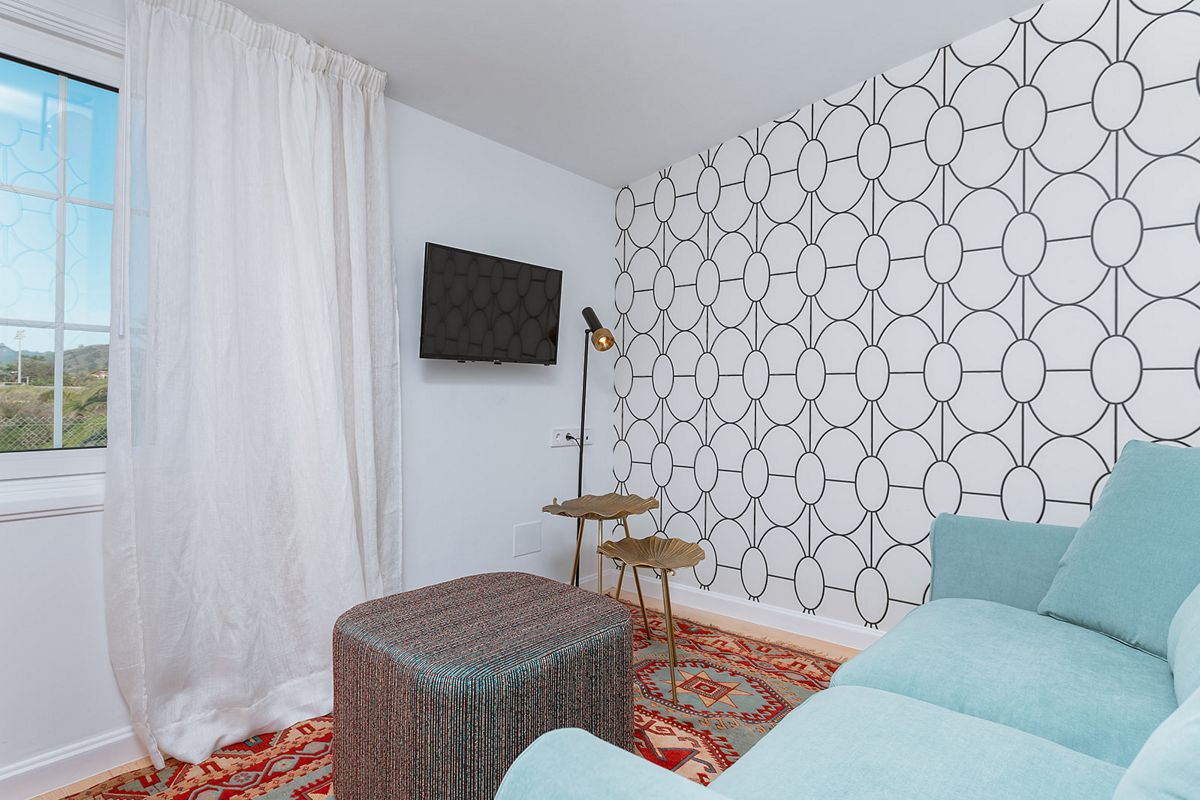 Wohnzimmer mit türkisfarbenem Sofa, gemustertem Teppich und Fernsehgerät in La Laguna.