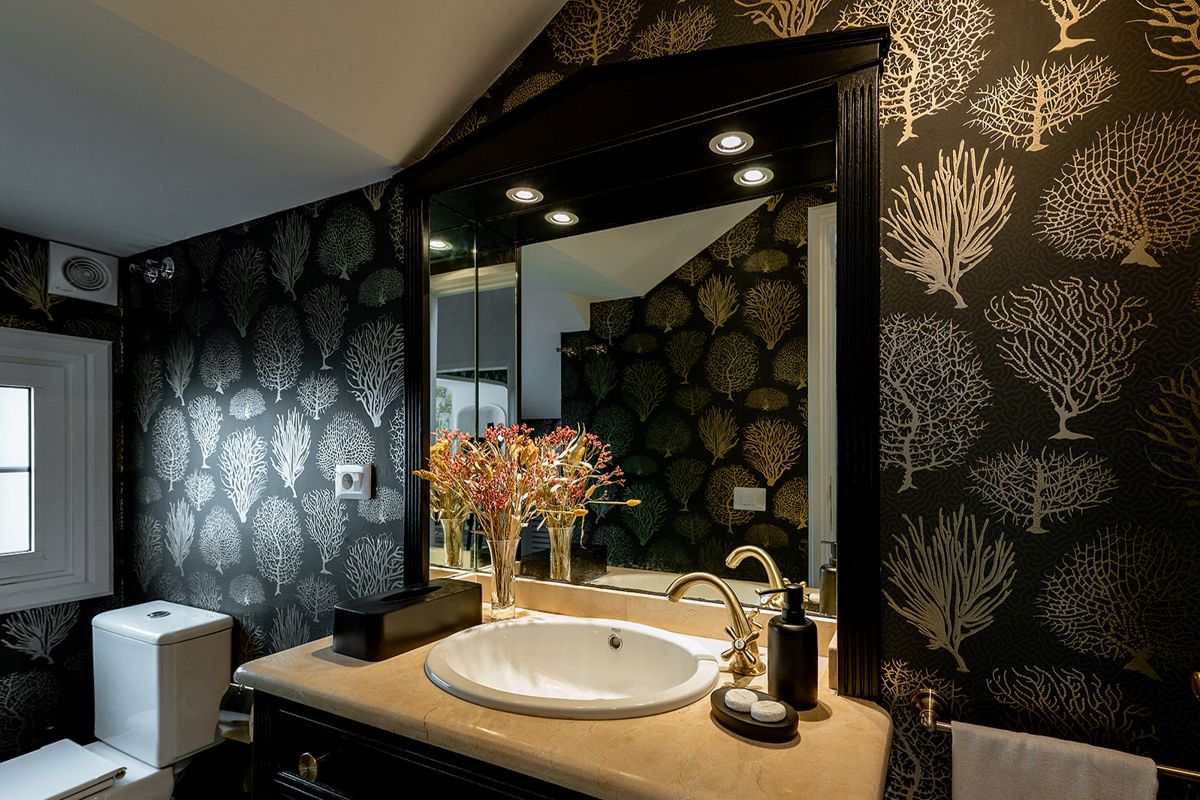 Waschbecken mit Spiegel, gemusterten Tapeten und Blumen im Badezimmer in Tenerife.
