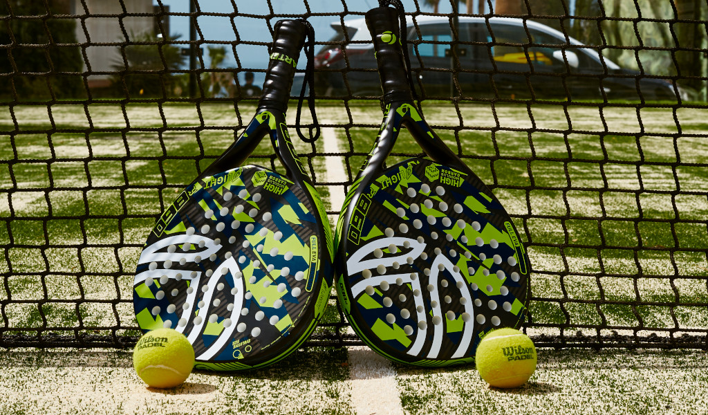 Zwei Padel-Schläger und Bälle auf Tennisplatz in Tenerife vor einem Netz.