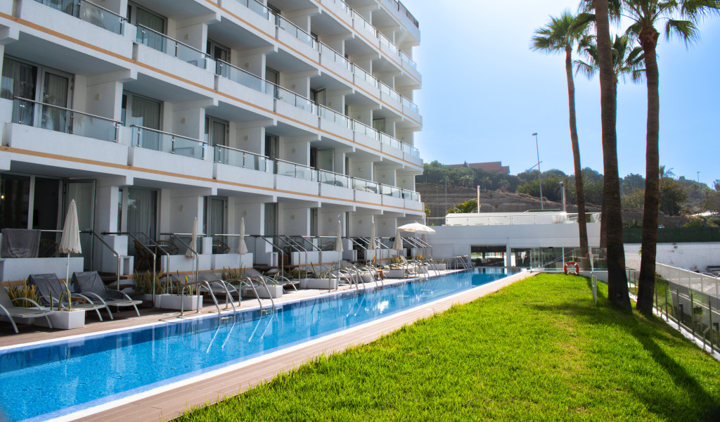 Außenansicht eines Hotels in Teneriffa mit Pool und Liegestühlen.