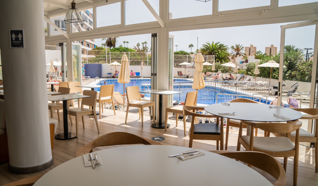 Essbereich mit Blick auf Pool in Hotel in Teneriffa, Gäste sonnen sich.