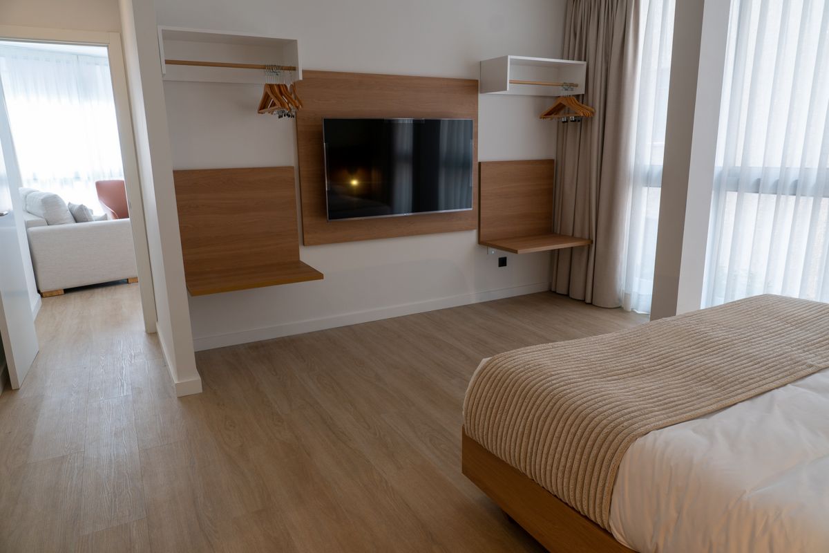 Modernes Hotelzimmer mit Fernseher, zwei Regalen und offenem Kleiderschrank in Teneriffa.