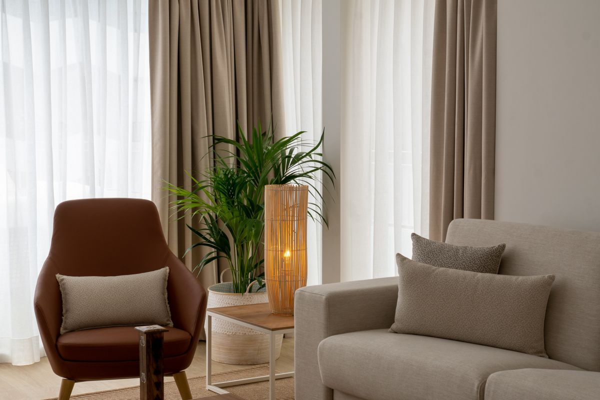 Brauner Sessel, weiße Couch, Holzlampe und Grünpflanze in modernem Wohnzimmer in Tenerife.
