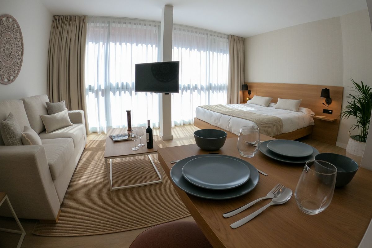 Modernes Apartmentzimmer in Tenerife mit Sofa, Bett und Esstisch.