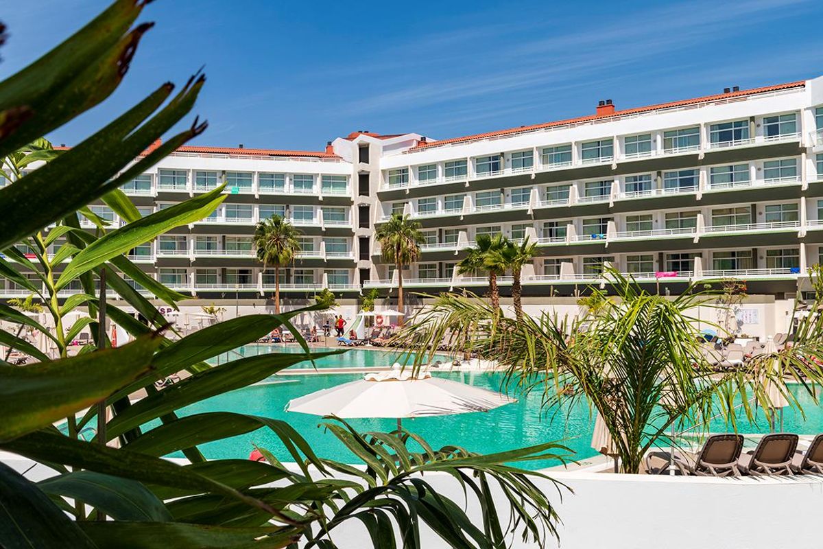 Mehrstöckiges Hotel mit Pool und Palmen in Arona, Teneriffa.