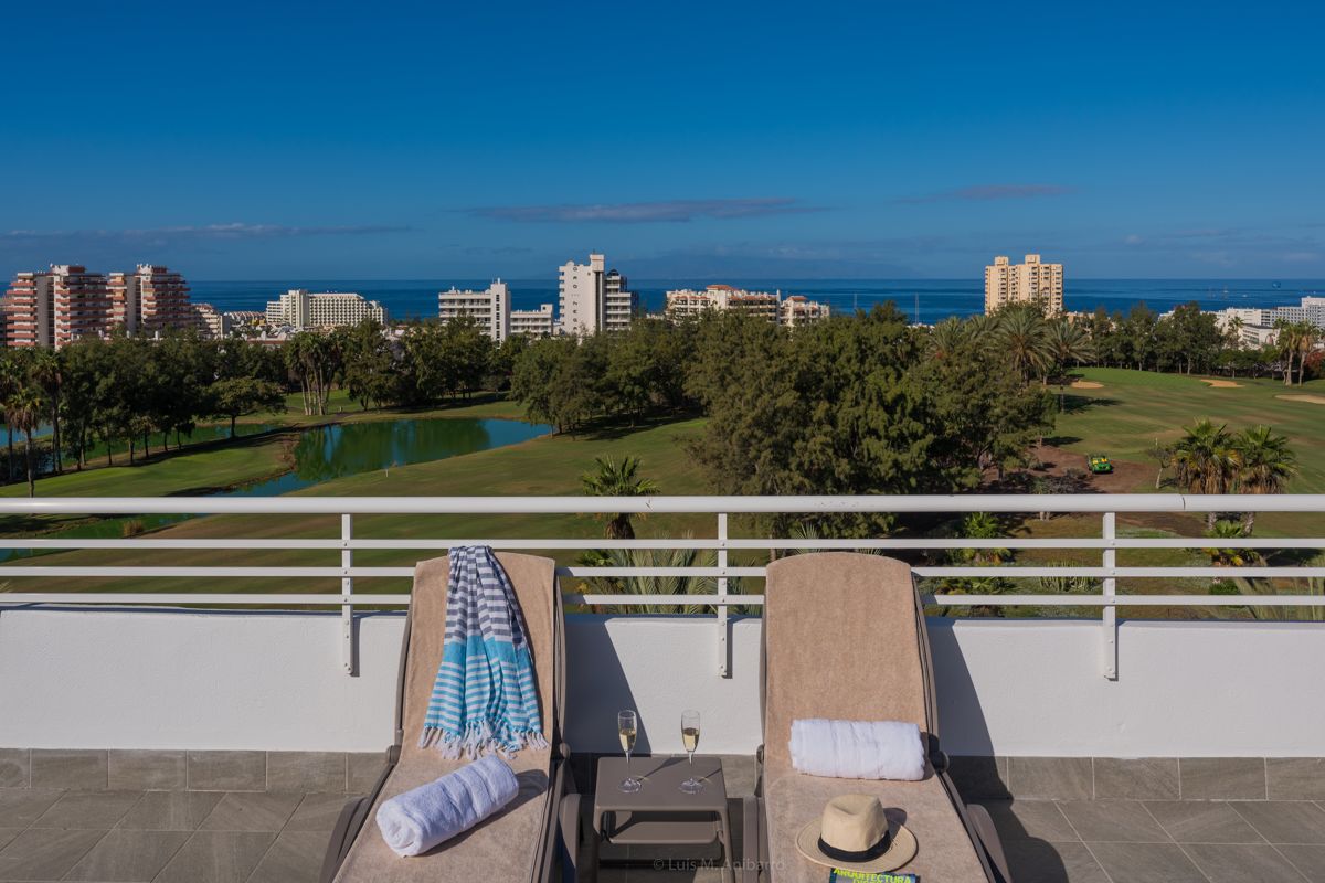Zwei Sonnenliegen auf Terrasse mit Blick auf Golfplatz und Meer in Teneriffa.