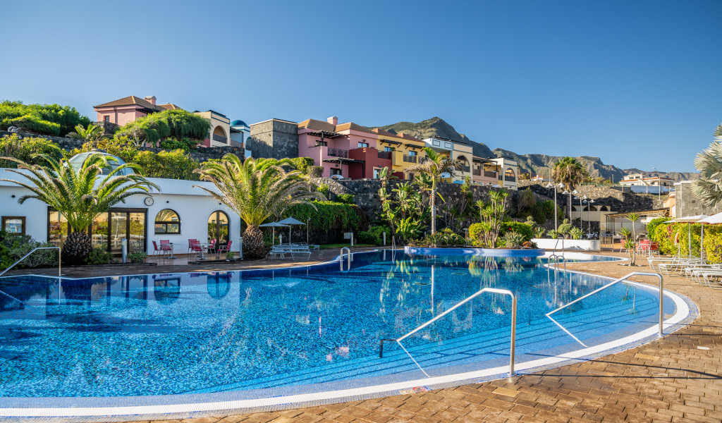 Großer Pool mit Palmen und Gebäuden im Hintergrund in Costa Adeje, Teneriffa.